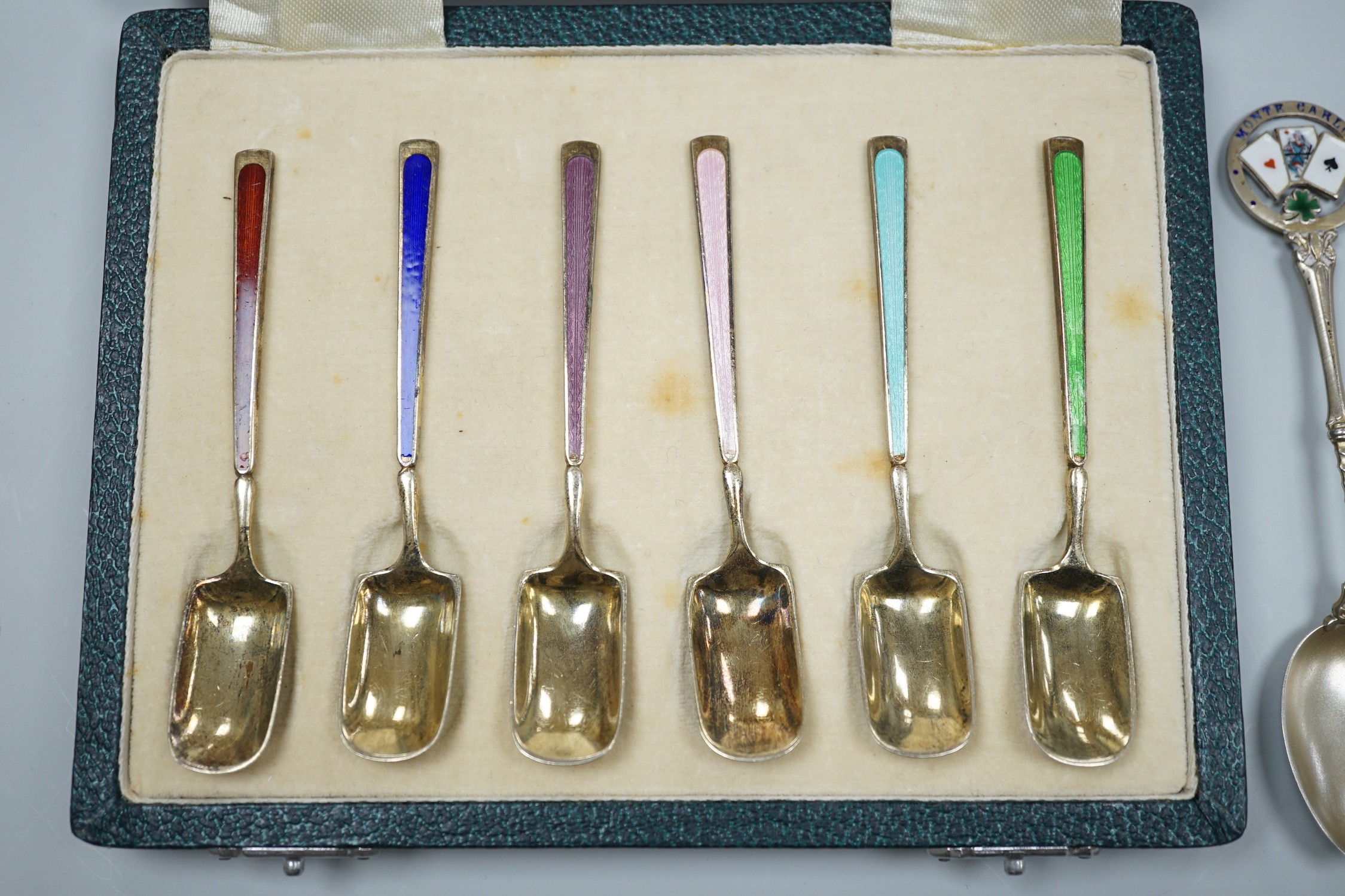 A cased set of six George V silver and polychrome enamel coffee spoons, Barker Bros. Silver Ltd, Birmingham, 1933 and two similar souvenir spoons.